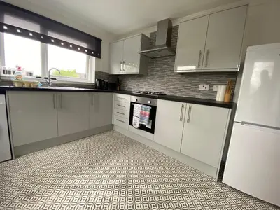 a kitchen with white cabinets and a tile floor at Pure Apartments Fife - Dunfermline West in Oakley