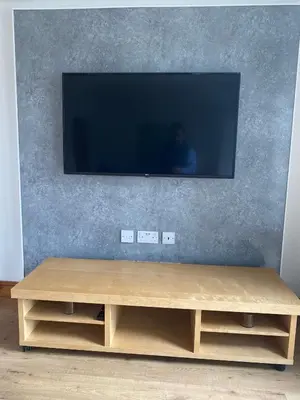 a wooden entertainment center with a flat screen tv on a wall at Pure Apartments Fife - Dunfermline West in Oakley