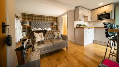 a living room with a couch and a kitchen at Nether Glenny Farm in Stirling