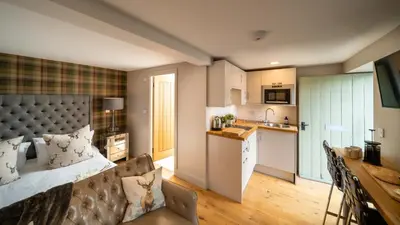 a bedroom with a large bed and a kitchen at Nether Glenny Farm in Stirling