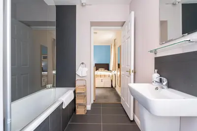 a bathroom with a white tub and a sink at NEW Four Bedroom House - all rooms ensuite in Stirling