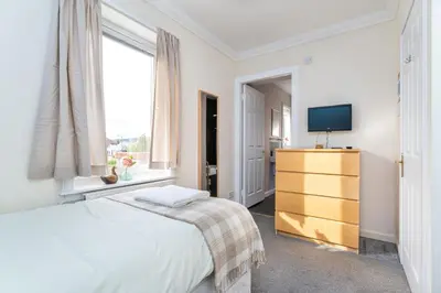 a bedroom with a bed and a tv and a window at NEW Four Bedroom House - all rooms ensuite in Stirling