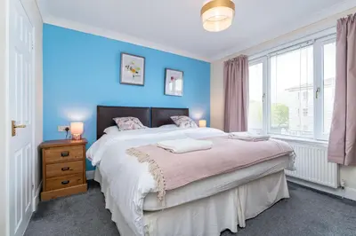 a bedroom with a large bed with blue walls at NEW Four Bedroom House - all rooms ensuite in Stirling