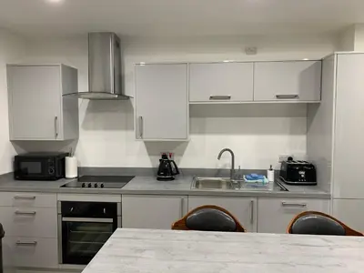 a kitchen with white cabinets and a table with chairs at Tanllan Apartment in Callander