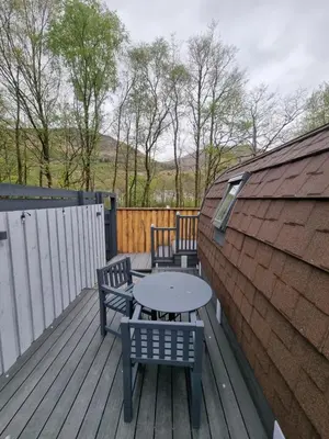 a patio with two benches and a table on a deck at Riverside Pod, West Highland Way Holidays in Kinlochleven