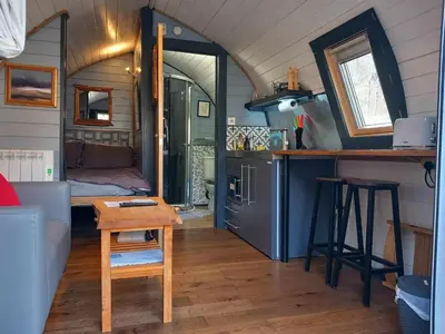 a living room with a kitchen and a room with a table at Riverside Pod, West Highland Way Holidays in Kinlochleven