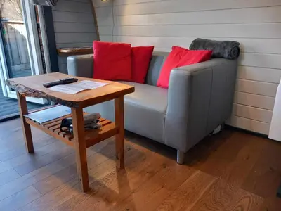 a couch with red pillows sitting next to a table at Riverside Pod, West Highland Way Holidays in Kinlochleven
