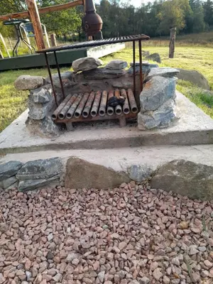 a stone patio with a grill and rocks at Sunset View Shepherds Hut in Dalmally