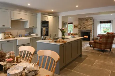 a kitchen with a table and chairs and a fireplace at Coach House in Perth