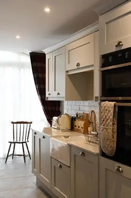 a kitchen with white cabinets and a stove top oven at Coach House in Perth