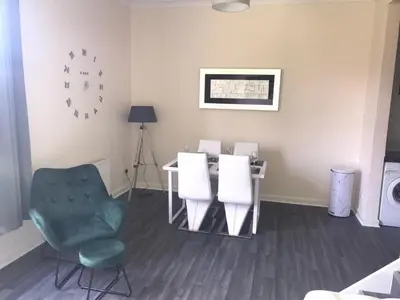 a living room with a table and a chair and a table at Vogue Apartments in Glasgow