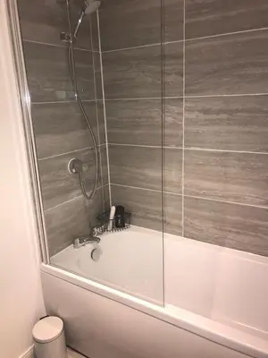 a bath tub with a glass shower in a bathroom at Vogue Apartments in Glasgow