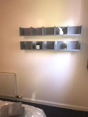 two shelves on a wall with a cat sitting on it at Vogue Apartments in Glasgow