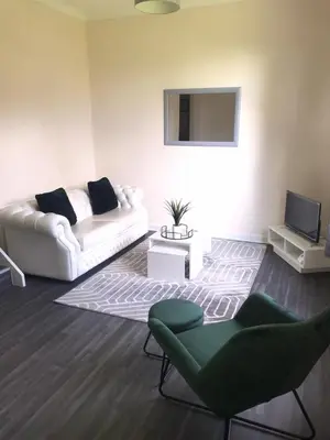 a living room with a white couch and a television at Vogue Apartments in Glasgow