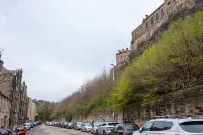 a street with cars parked on the side of a wall at Charming Grassmarket 1 Bed Castle pad in Edinburgh