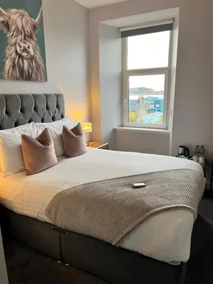 a bedroom with a large bed with a lion picture on the wall at Killorn Guest House in Oban