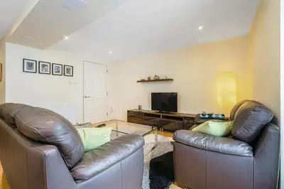 a living room with two leather couches and a television at Bell Street Apartments in Glasgow