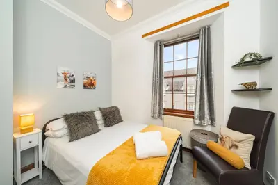 a bedroom with a bed and a chair and a window at The Tollbooth in Clackmannan