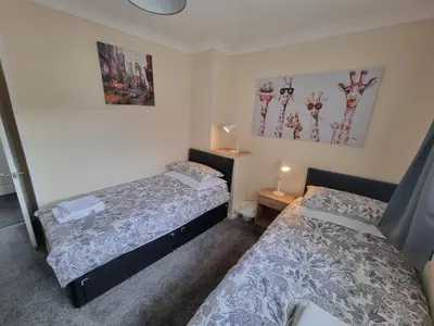 two beds in a small room with two lamps at Hamilton Home From Home in Hamilton
