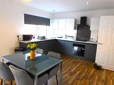 a kitchen with a table and chairs in a room at Newly refurbished 2 bedroom apartment close to station and local amenities in Hamilton