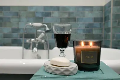 a candle and a glass of wine on a bathroom counter at Blackmount House in Oban