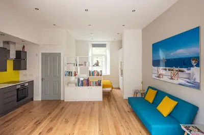 a living room with a blue couch and a kitchen at Artist's Studio in Stockbridge in Edinburgh