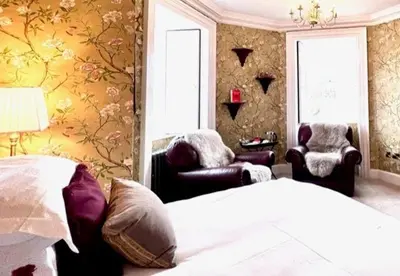 a bedroom with a bed and two chairs in a room at Moffat House in Moffat