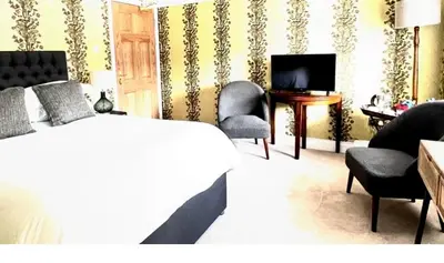 a bedroom with a bed and chairs and a television at Moffat House in Moffat