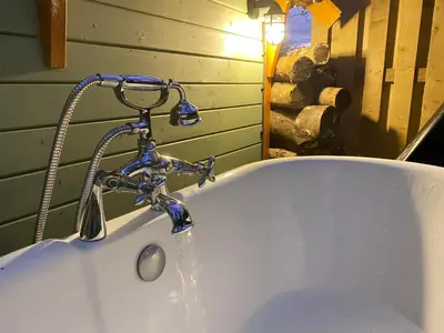 a bath tub with a faucet with water coming out at 1-Bed Cabin 2 Adults Outdoor Bath & Wood Burner in Carluke
