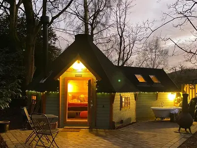 a small house with a lighted roof and a tub at 1-Bed Cabin 2 Adults Outdoor Bath & Wood Burner in Carluke