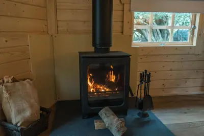 a stove in the corner of a room at 1-Bed Cabin 2 Adults Outdoor Bath & Wood Burner in Carluke