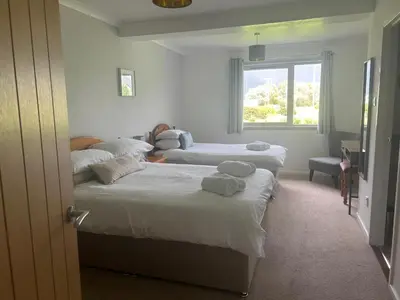 a bedroom with three beds and a window at Lyn leven cottages in Ballachulish