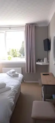 a bedroom with a bed and a window and a desk at CORSBIE VILLA GUEST HOUSE in Newton Stewart