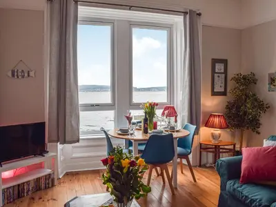 a living room with a table and a large window at The Seaside Suite in Helensburgh