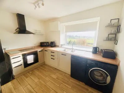 a kitchen with a sink and a washing machine at AIRDSIDE COTTAGE in Castle Douglas