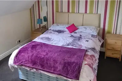 a bedroom with a bed with a purple blanket on it at 4 Bed Cottage Sleeps 6-Pet-Friendly-Private Garden in Campbeltown