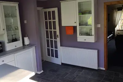 a kitchen with white cabinets and a purple wall at 4 Bed Cottage Sleeps 6-Pet-Friendly-Private Garden in Campbeltown
