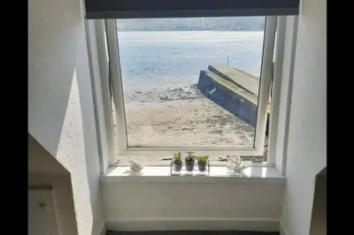 an open window with a view of the beach at Loch Views Apartment Sleeps 2-Pets Ok-Free Parking in Campbeltown