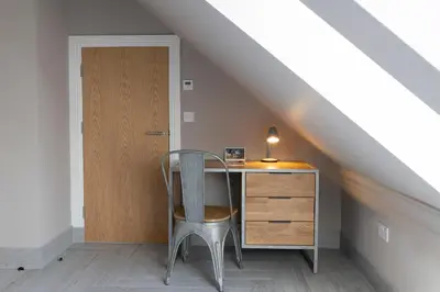 an attic room with a desk and a chair at Westertonhill Lodges - Private Hot Tub Hire Available in Balloch