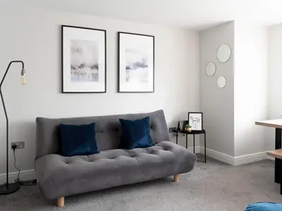 a living room with a gray couch with blue pillows at Lovely, comfortable 2-bed Braehead - free parking - Pass the Keys in Renfrew