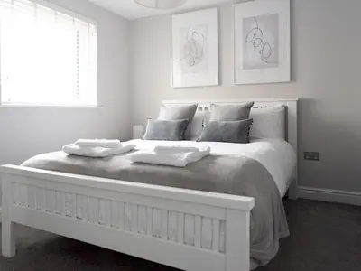 a white bedroom with a large white bed with pillows at Lovely, comfortable 2-bed Braehead - free parking - Pass the Keys in Renfrew