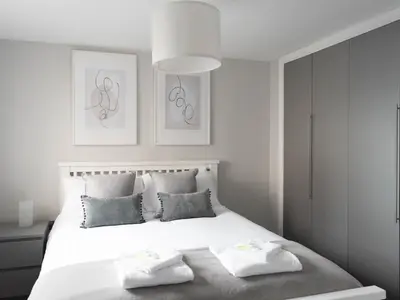 a white bedroom with a large white bed with two pillows at Lovely, comfortable 2-bed Braehead - free parking - Pass the Keys in Renfrew