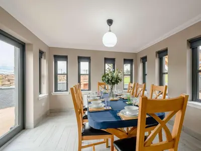 a dining room with a table and chairs and windows at Westertonhill Holiday Lodges - Private Hot Tub Hire Available in Balloch
