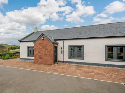 a white house with a brick garage at Westertonhill Holiday Lodges - Private Hot Tub Hire Available in Balloch