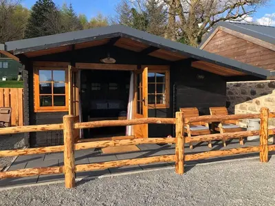 a cabin with a wooden fence in front of it at 1 Bed Cabin in the Magical Galloway Forest Park in Newton Stewart