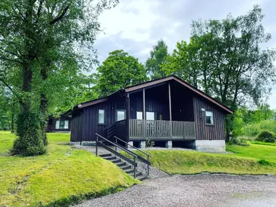 a large house with a porch and a tree at Cherry tree Lodge in Dunoon