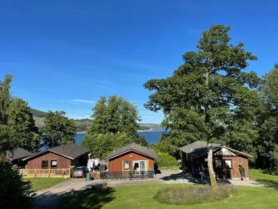 a group of cottages with a lake in the background at Cherry tree Lodge in Dunoon