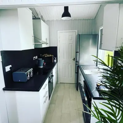 a kitchen with white cabinets and a black counter top at Cherry tree Lodge in Dunoon