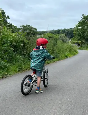 a young child riding a bike on a road at The Wee Shop, Stylish Two Bed Flat in Inverkip Village in Inverkip