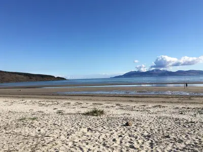 a beach with two people walking on the sand at Taigh An Uillt in Tighnabruaich